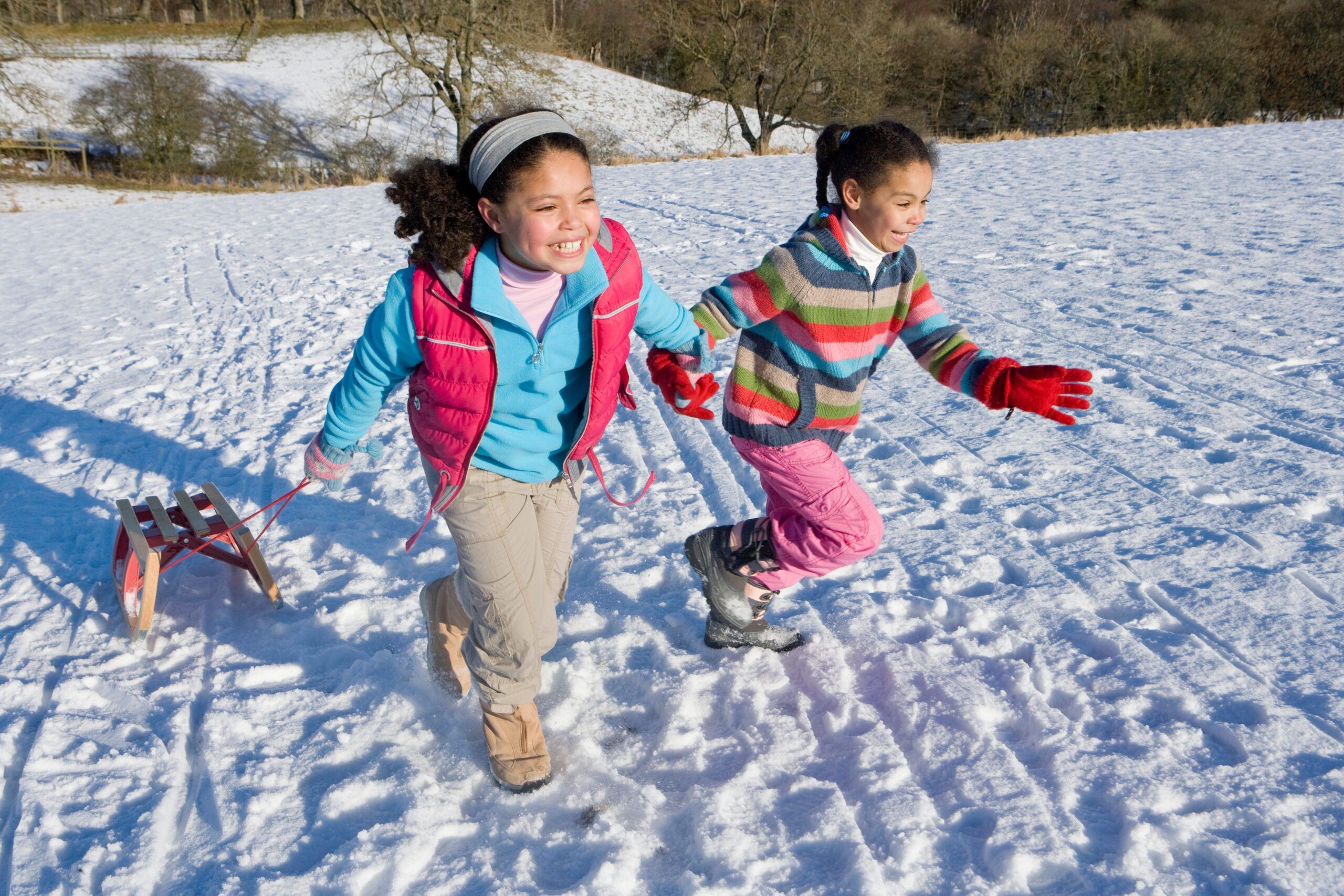 Two Girls Sledding in Snow