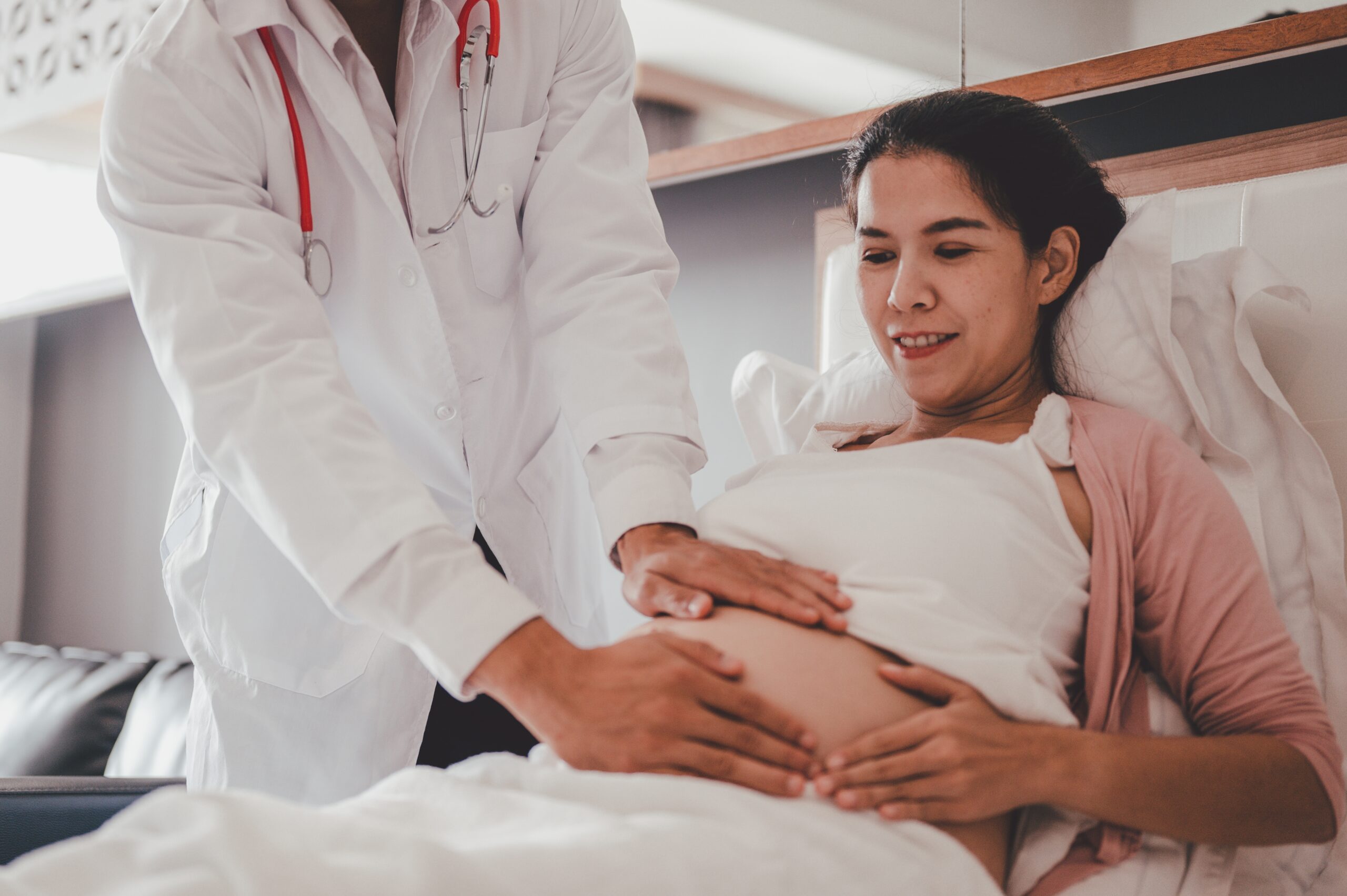 Doctor assisting a pregnant woman in a hospital bed.